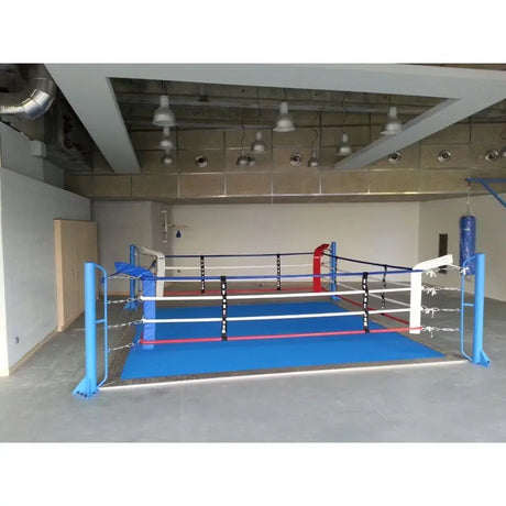 SportCom Ecofix Bodenmontage-Boxring mit Aluminiumrand, in einer leeren Halle mit blauem Boden