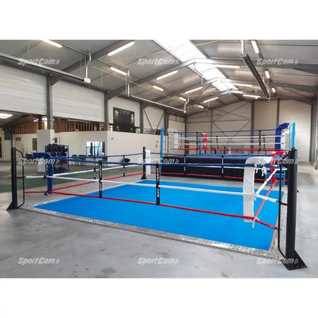 SportCom Ecofix Bodenmontage-Boxring mit Aluminiumrand, in einer Lagerhalle mit blauem Boden und weißer Ecke