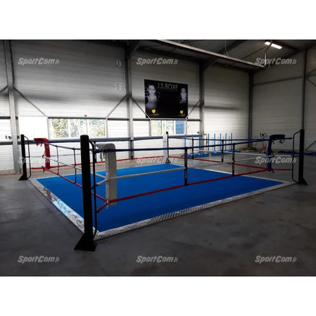 SportCom Ecofix Bodenmontage-Boxring mit Aluminiumrand, in einer Lagerhalle mit blauem Boden, seitlich