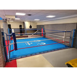 SportCom Ecofix Bodenmontage-Boxring mit Spannseilen, mit blauem Boden und Logo in einem Gym