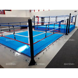 SportCom Ecofix Bodenmontage-Boxring mit Spannseilen, mit blauem Boden in einer Halle, Eckpfosten vorne