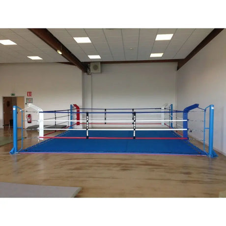 SportCom Ecofix Bodenmontage-Boxring mit Spannseilen, mit blauem Boden in einer weiten Halle