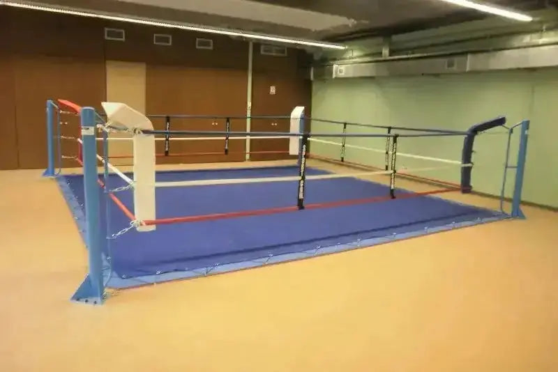 SportCom Ecofix Boxring mit Spannseil-Plane auf orangefarbenem Hallenboden mit blauen Eckpolstern