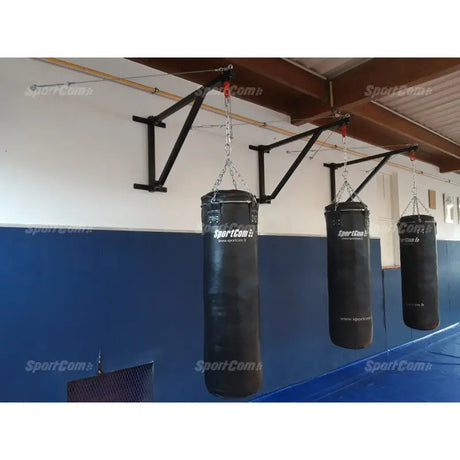 SportCom Feste Sandsackhalterung mit Stabilisierung, drei Halterungen mit Sandsäcken an blauer Hallenwand