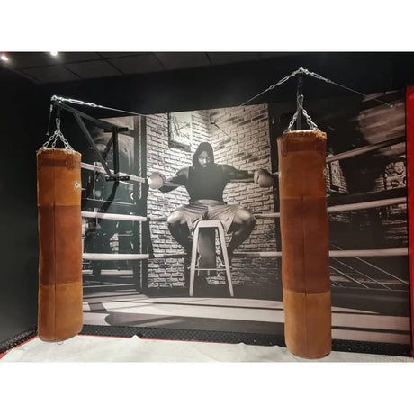 SportCom Feste Sandsackhalterung mit Stabilisierung, zwei braune Ledersäcke vor Fotowand im Boxstudio