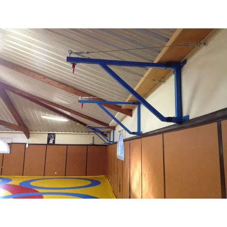 SportCom Feste Sandsackhalterung mit Stabilisierung, blaue Ausleger unter Holzdecke einer Ringerhalle
