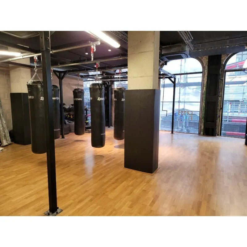 SportCom Flexi-Post Säulenpolster von Dollamur an mehreren Säulen einer Halle mit Boxsäcken