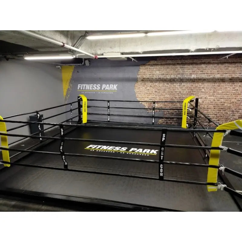 SportCom Flexi-Roll Mattenfläche für Boxringe in einem Ring mit gelben Eckpolstern im Fitnessstudio