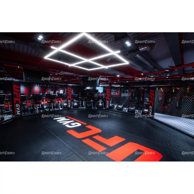 SportCom Flexi-Roll Mattenfläche für MMA-Käfige, verlegt in einem beleuchteten Gym mit rotem Logo auf der Fläche