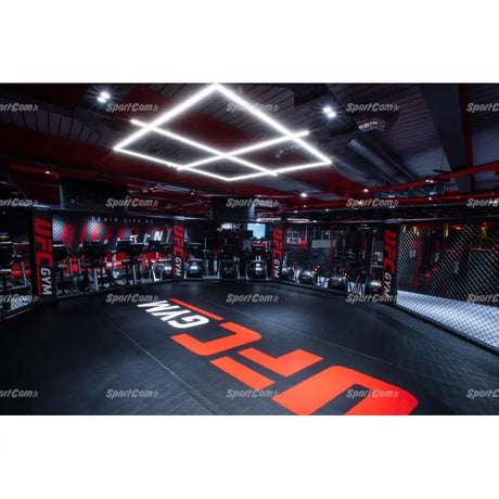 SportCom Flexi-Roll Mattenfläche für MMA-Käfige, verlegt in einem beleuchteten Gym mit rotem Logo auf der Fläche