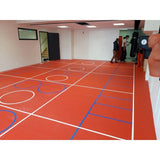 SportCom Flexi-Roll Ringermatte von Dollamur, rote Fläche mit Spielfeldlinien in einer Halle