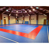SportCom Flexi-Roll Ringermatte von Dollamur, blaue Fläche mit rotem Rahmen in einer Halle mit Holzdecke