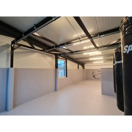 SportCom Flexi-Roll Ringermatte von Dollamur, hellgraue Fläche in schmalem Trainingsraum mit Sandsack