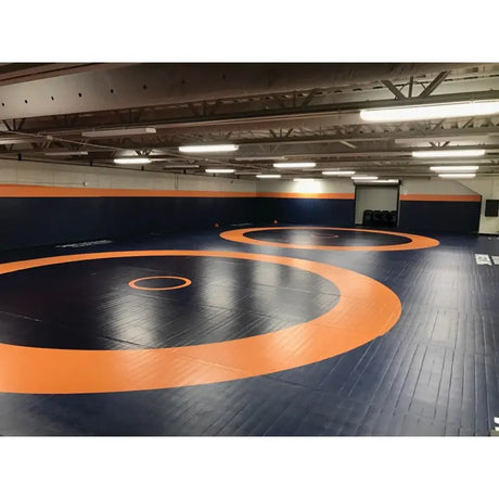 SportCom Flexi-Roll Ringermatte von Dollamur, dunkelblaue Mattenfläche mit orangen Ringerkreisen in einer Halle