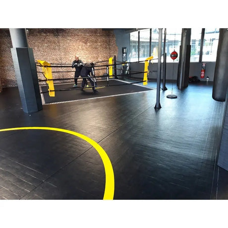 SportCom Flexi-Roll Ringermatte von Dollamur, schwarze Fläche mit gelber Linie und Boxring im Studio