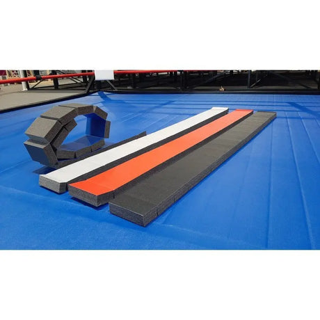 SportCom Flexi-Roll Schwebebalken auf blauer Wettkampfmatte, Balken in Weiß, Rot und Schwarz neben einer Rolle