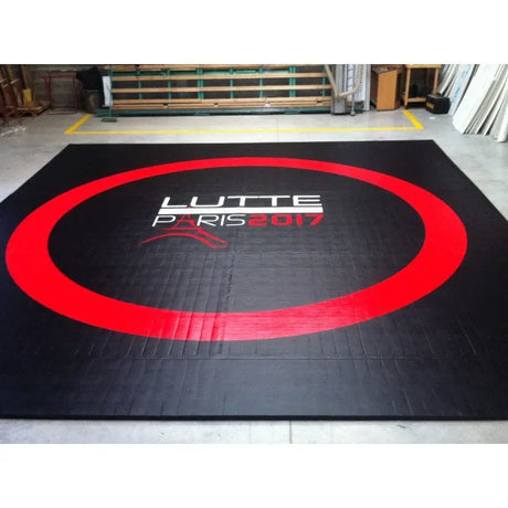 SportCom Flexi-Roll Wrestling Studio-Matte in Schwarz mit rotem Kreis und Aufdruck in einer Halle