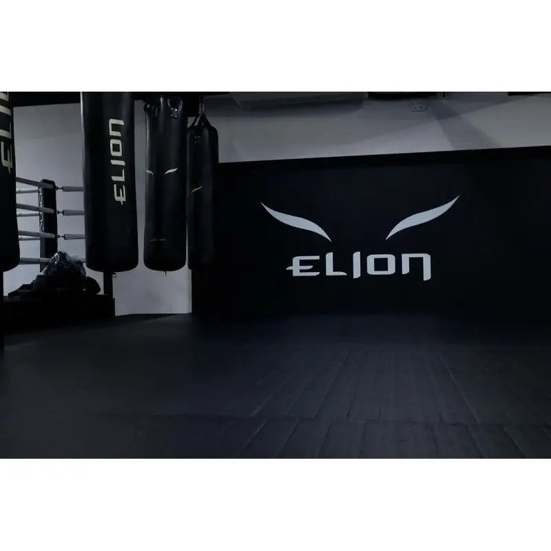 SportCom Flexi-Wall Wandschutz von Dollamur in Schwarz hinter Boxsäcken mit Logo an der Wand