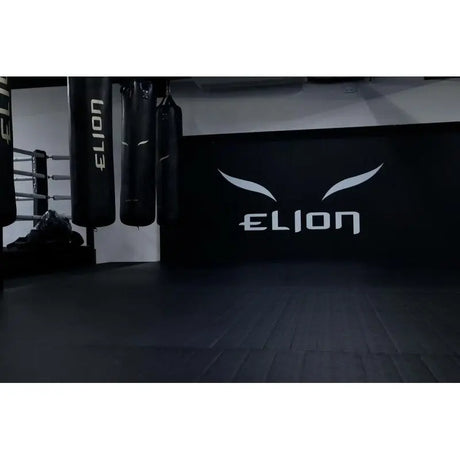 SportCom Flexi-Wall Wandschutz von Dollamur in Schwarz hinter Boxsäcken mit Logo an der Wand