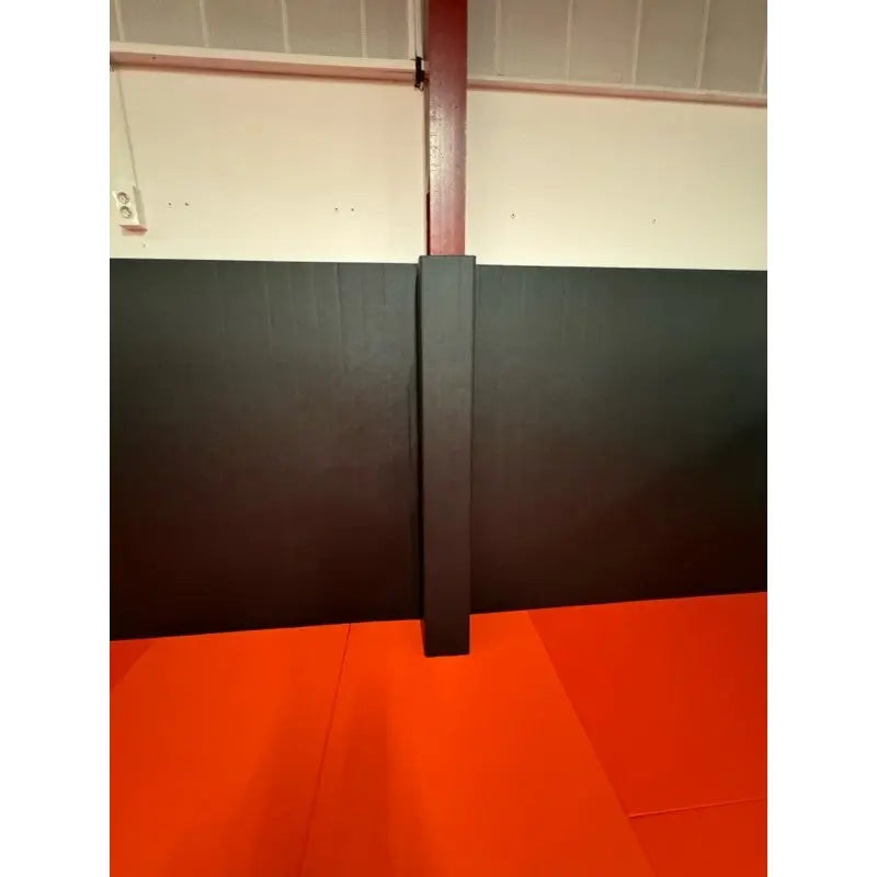 SportCom Flexi-Wall Wandschutz von Dollamur in Schwarz, Detail um eine Säule über orangem Boden