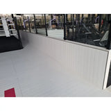 SportCom Flexi-Wall Wandschutz von Dollamur in Weiß an einer Glasfront über hellem Boden