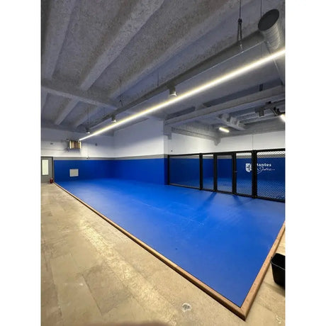 SportCom Flexi-Wall Wandschutz von Dollamur in Blau an einer Glaswand eines schmalen Raums