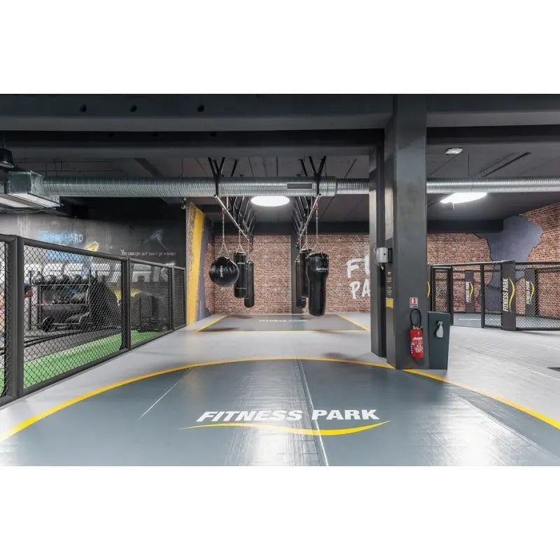 SportCom Flexi-Wall Wandschutz von Dollamur in Grau in einem Gym mit Käfig und Bodenmarkierung