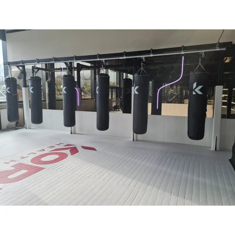 SportCom Förderschiene mit Rahmen für Sandsäcke, in einem Gym mit bedrucktem Boden und violetter Leuchte