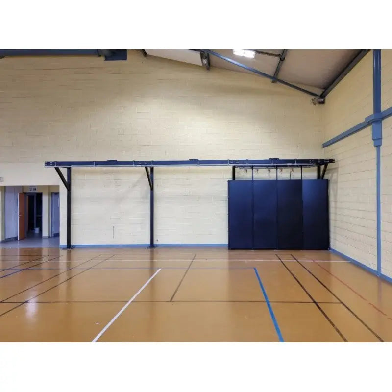 SportCom Förderschiene mit Rahmen für Sandsäcke, in einer Sporthalle an der Wand montiert, ohne Säcke