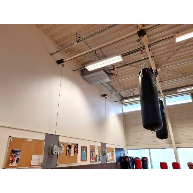 SportCom Handwinde für Sandsäcke in einer Sporthalle, schwarze Sandsäcke an der Deckenschiene