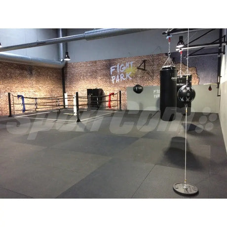 SportCom Judo-Tatami Reisstroh 1 × 1 m, 5 cm, rutschfeste Unterseite, dunkle Fläche vor Backsteinwand mit Boxring