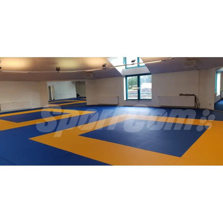 SportCom Judo-Tatami Reisstroh 1 × 1 m, 5 cm, rutschfeste Unterseite, blaue und gelbe Flächen in hellem Raum, Querformat