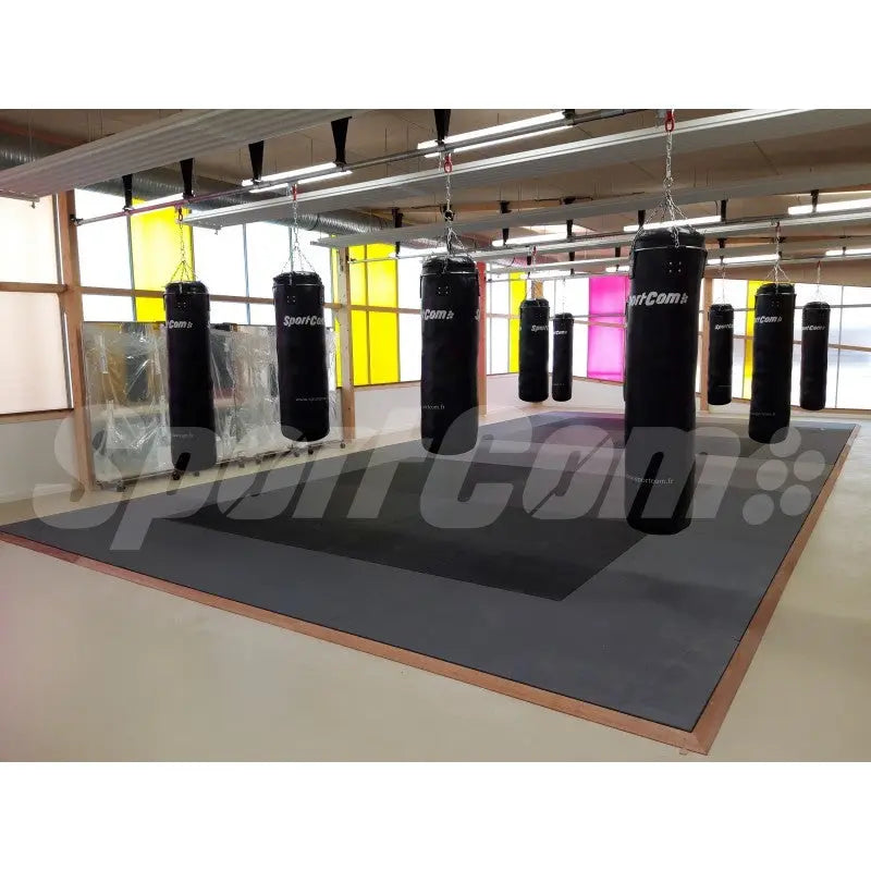 SportCom Judo-Tatami Reisstroh 1 × 1 m, 5 cm, rutschfeste Unterseite, dunkle Fläche unter Sandsäcken in einem Studio