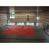 SportCom Judo-Tatami Reisstroh 2 × 1 m, 5 cm, glatte Unterseite, rote Fläche mit grauem Rand im Dojo mit Kanji an der Wand