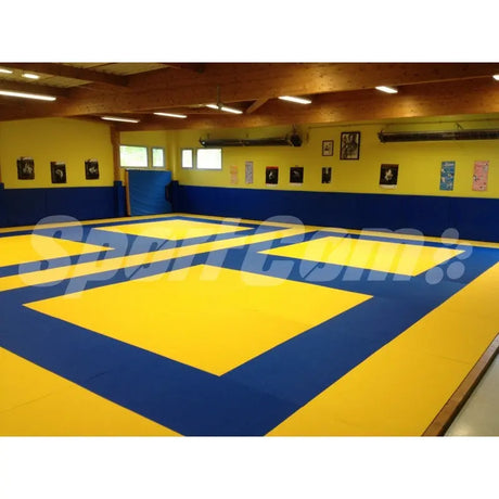 SportCom Judo-Tatami Reisstroh 2 × 1 m, 5 cm, glatte Unterseite, zwei gelbe Kampfzonen auf Blau im Dojo mit Bildern an der Wand
