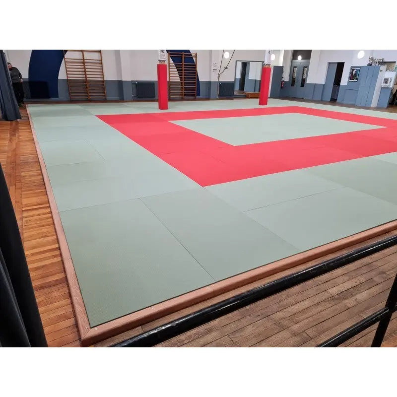 SportCom Judo-Tatami Reisstroh 2 × 1 m, 5 cm, glatte Unterseite, grün-rote Fläche mit Holzrahmen neben einem Geländer