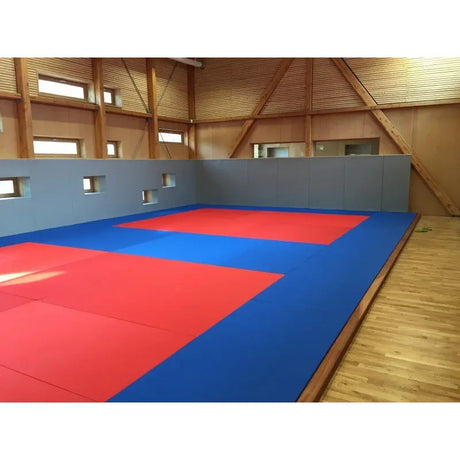 SportCom Judo-Tatami Reisstroh 2 × 1 m, 5 cm, glatte Unterseite, blaue Fläche mit roter Zone auf Holzboden in einer Holzhalle