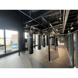 SportCom Kunstleder-Sandsack 1,80 m in Reihe an Fensterfront eines Industriestudios