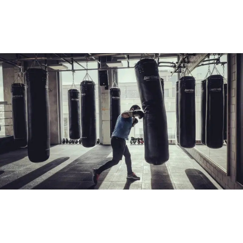SportCom Kunstleder-Sandsack 1,80 m im Einsatz beim Boxtraining in einer Halle mit mehreren Säcken