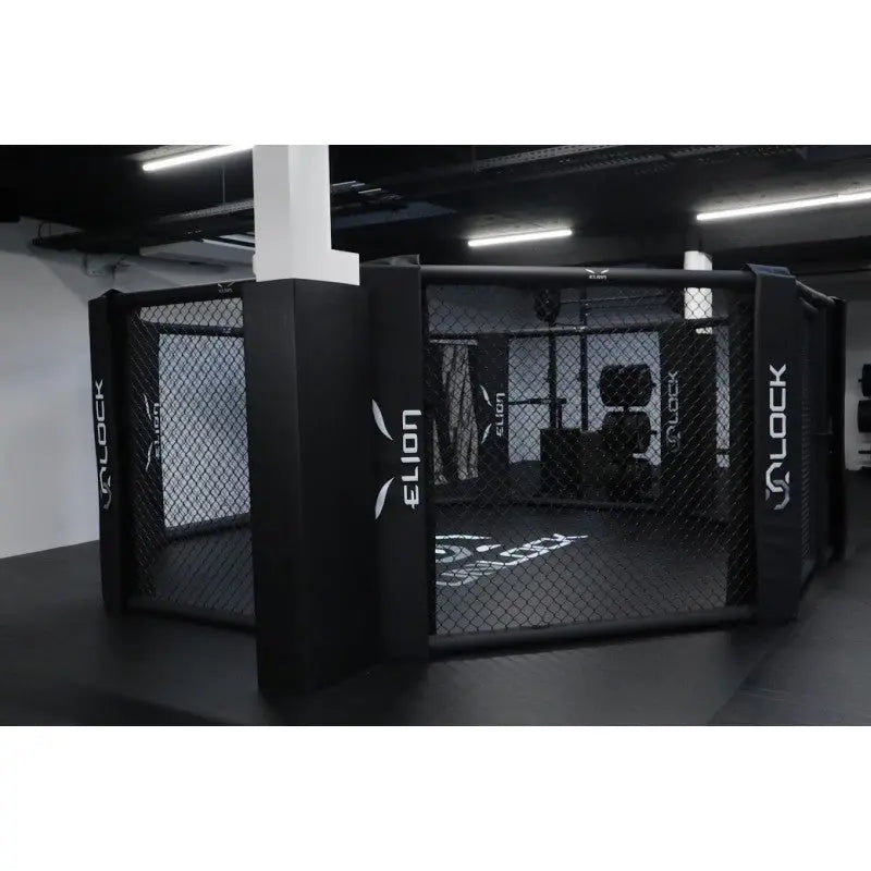 SportCom MMA-Käfig-Individualisierung: schwarzer Käfig mit Logo-Polstern, seitliche Ansicht in der Halle
