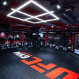 SportCom MMA-Käfig-Individualisierung: schwarzer Boden mit großem roten Schriftzug in einem Studio