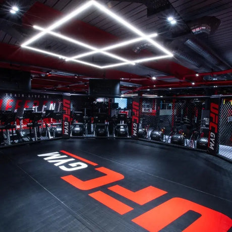 SportCom MMA-Käfig-Individualisierung: schwarzer Boden mit großem roten Schriftzug in einem Studio