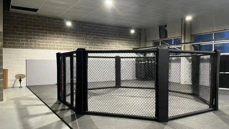 SportCom MMA-Käfig Oktagon zur Bodenmontage, in einer Halle mit blauen Fenstern, seitlich
