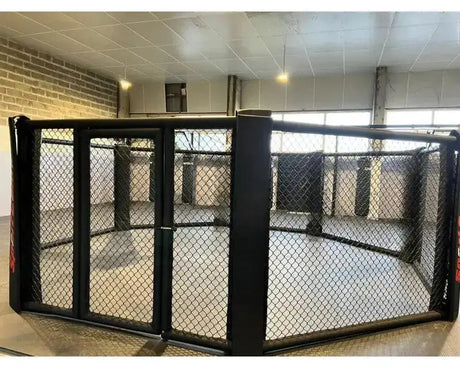 SportCom MMA-Käfig Oktagon zur Bodenmontage, in einer Halle mit Fensterfront, frontal auf die Tür