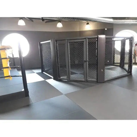 SportCom MMA-Käfig Oktagon zur Bodenmontage, in einem Studio mit runden Fenstern und grauem Boden