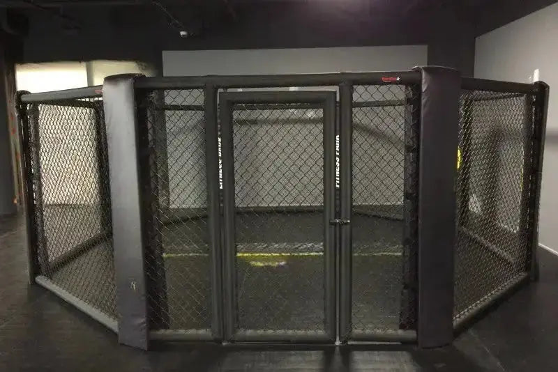 SportCom MMA-Käfig Oktagon zur Bodenmontage, frontal auf die Tür in einem dunklen Studio