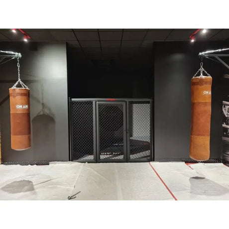 SportCom MMA-Paneel mit Tür als Käfigfront zwischen zwei braunen Boxsäcken