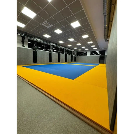 SportCom MMA-Tatami Glattfinish 1 × 1 m, 4 cm, rutschfeste Unterseite, erhöhte gelb-blaue Fläche in hoher Halle