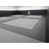 SportCom MMA-Tatami Glattfinish 1 × 1 m, 4 cm, rutschfeste Unterseite, Studio mit hellgrauen Feldern auf dunklem Grund