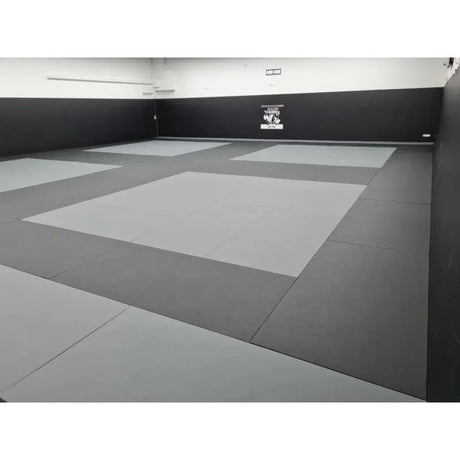 SportCom MMA-Tatami Glattfinish 1 × 1 m, 5 cm, glatte Unterseite, Studio mit hellgrauen Feldern auf dunklem Grund